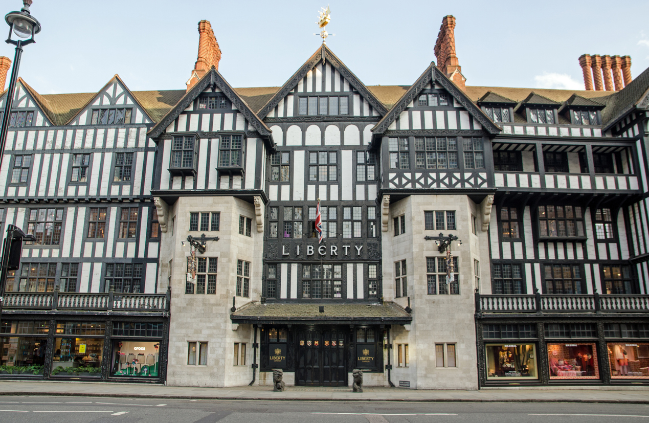 The Liberty department store in London boasts a striking Tudor-style facade with black and white timber framing, tall chimneys, and an ornate entrance. Located just a short walk from the elegant streets of Mayfair, its a must-see for any London shopping adventure.